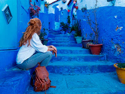 Vrouw zit op trap in de blauwe stad Chefchaouen in Marokko