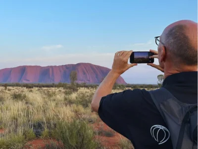 Man die met zijn mobiele telefoon een foto maakt van Uluru in Australië