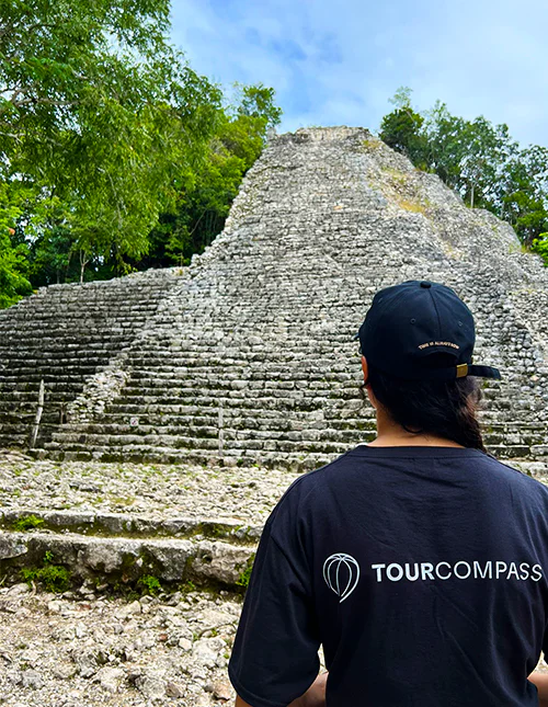 Een persoon draagt een TourCompass T-shirt en staat voor een Mayaruïne in Mexico