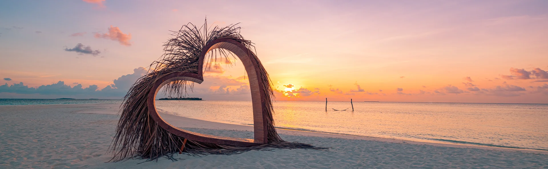 Hartsculptuur op een tropisch strand bij zonsondergang