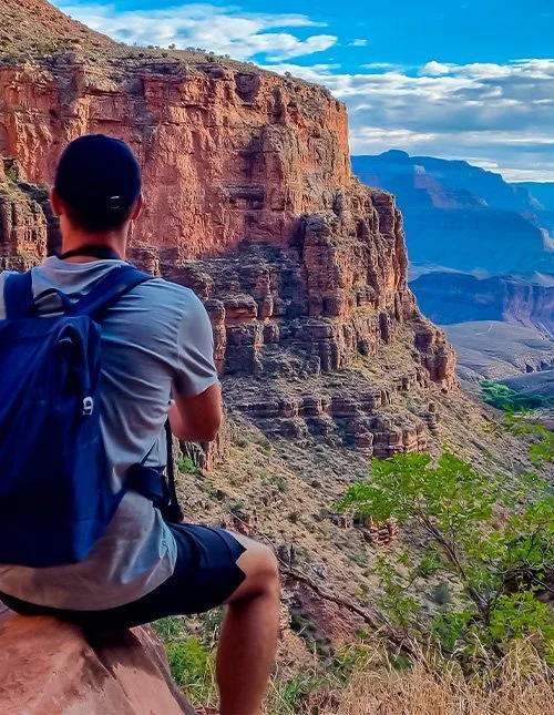 Man die op een klif langs de Bright Angel Trail staat en uitkijkt over de South Rim in het Grand Canyon National Park